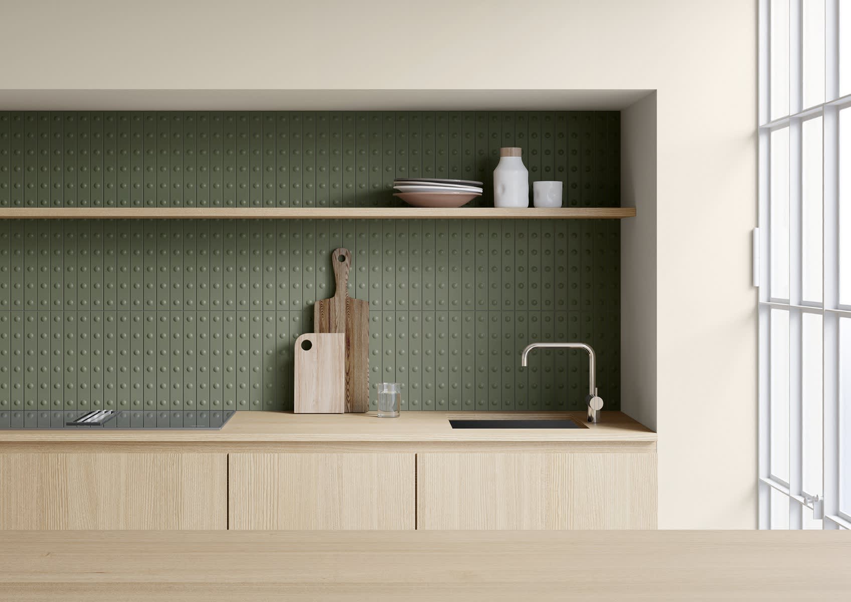 Mutina Punto glazed ceramic wall tiles in Vert green with raised dot texture installed as kitchen backsplash, wooden countertop with cutting boards, open shelf with ceramics, modern sink