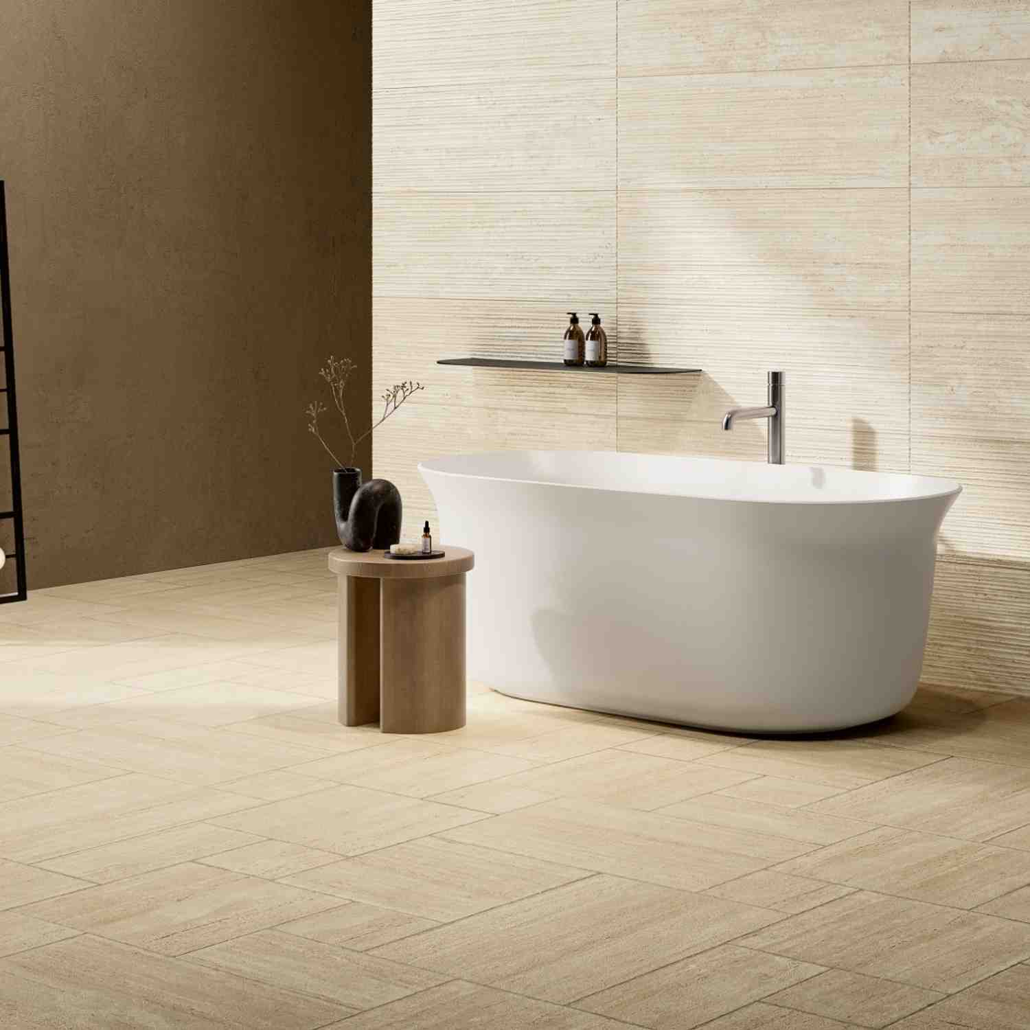 Ceramica Fioranese Senzatempo Trav porcelain stoneware tiles in Beige travertine-look on bathroom wall and floor with freestanding white bathtub, floating dark shelf with bath products, terracotta accent wall, wooden side table with dark ceramic vases in