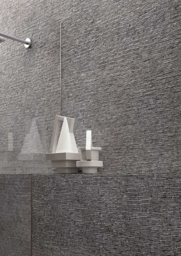 Ergon Stonetalk mosaic porcelain stoneware wall tiles in Dark Martellata hammered textured finish close-up vertical view showing contrasting surface textures with white geometric sculptural decorative objects and chrome shower fitting