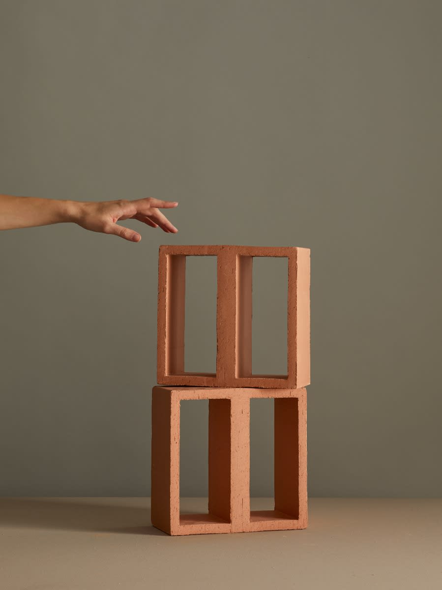 Mutina Tally Wide single terracotta module with hand for scale reference showing artisanal extruded block with rectangular openings in natural Argilla matte finish