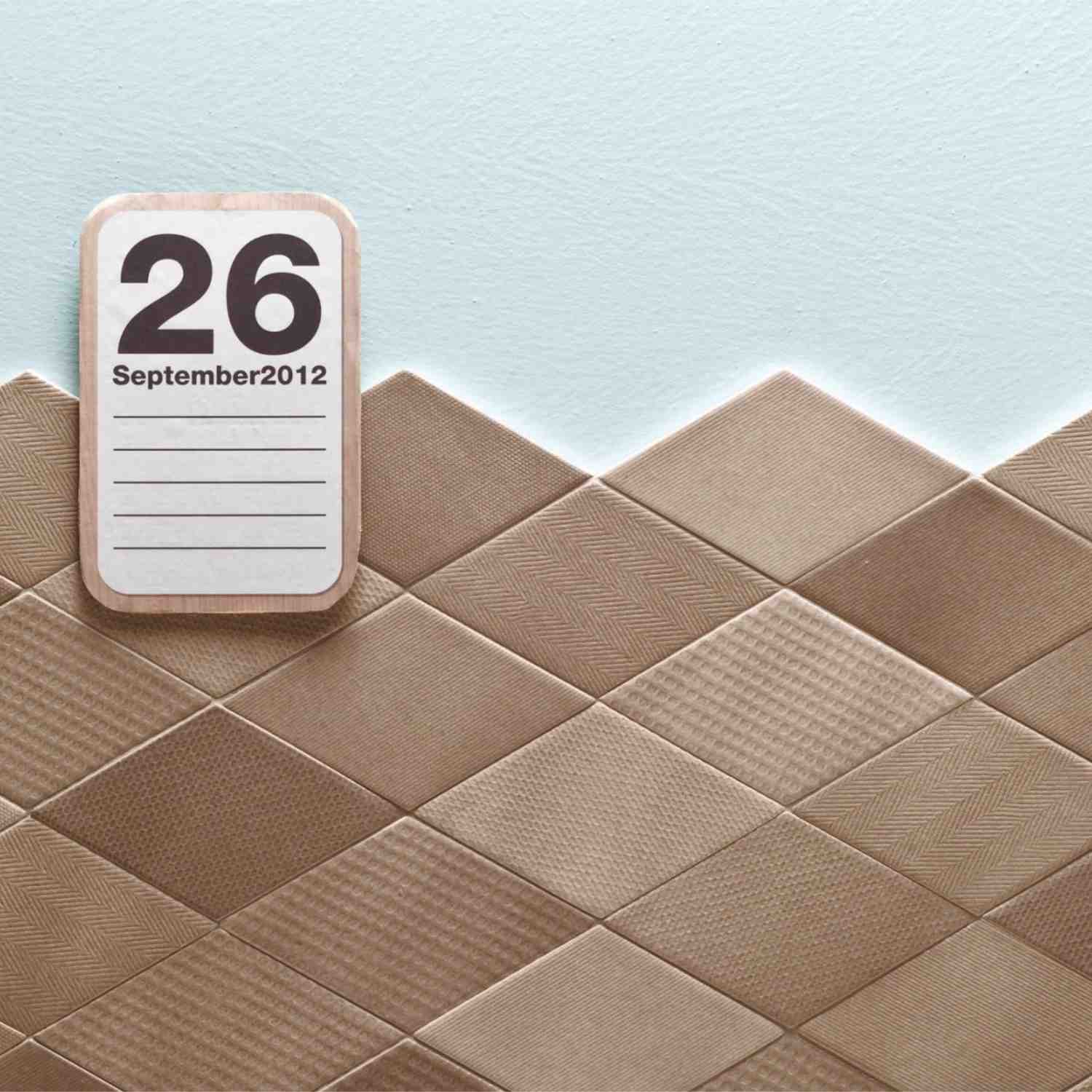 Mutina Tex ceramic wall tile detail with brown textured diamond-shaped tiles arranged diagonally against a light blue wall, styled with a vintage flip calendar