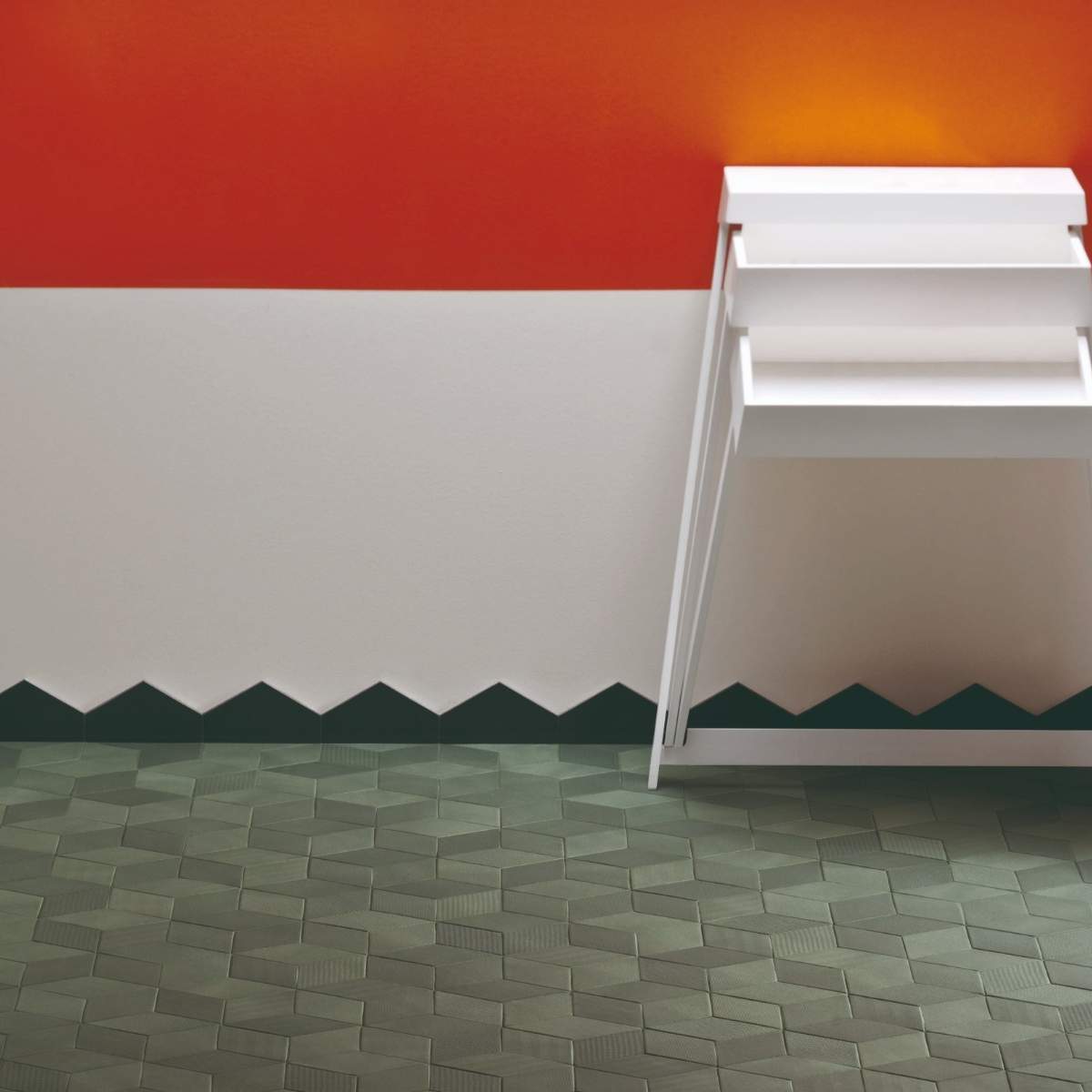Mutina Tex porcelain tile interior with bold red-orange and light grey walls, white floating shelves, and dark teal zigzag patterned tile baseboard detail