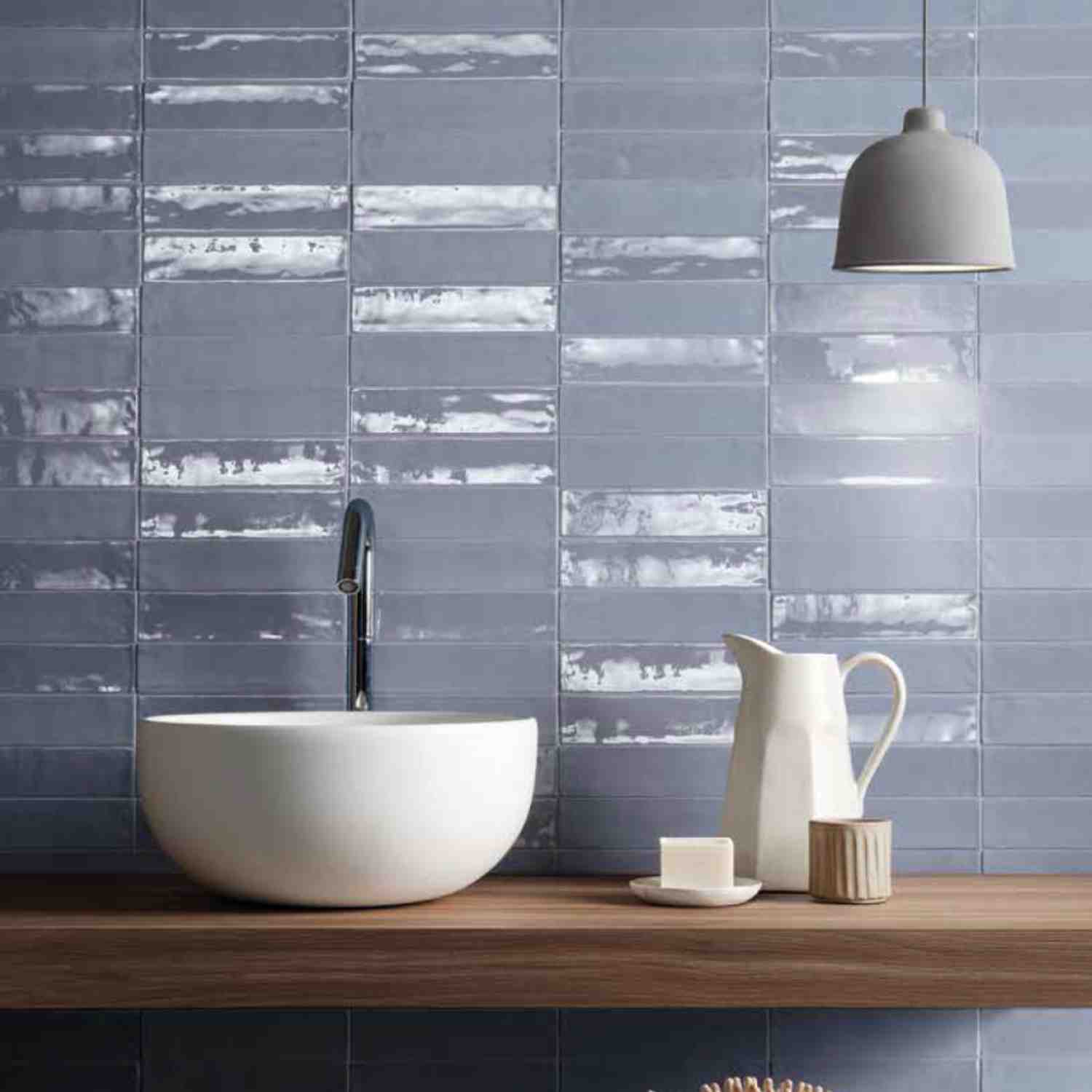 Ergon Total Brick glazed ceramic wall tiles in dark blue-grey installed in a modern bathroom with white vessel sink, matte black faucet, pendant light, and wooden vanity