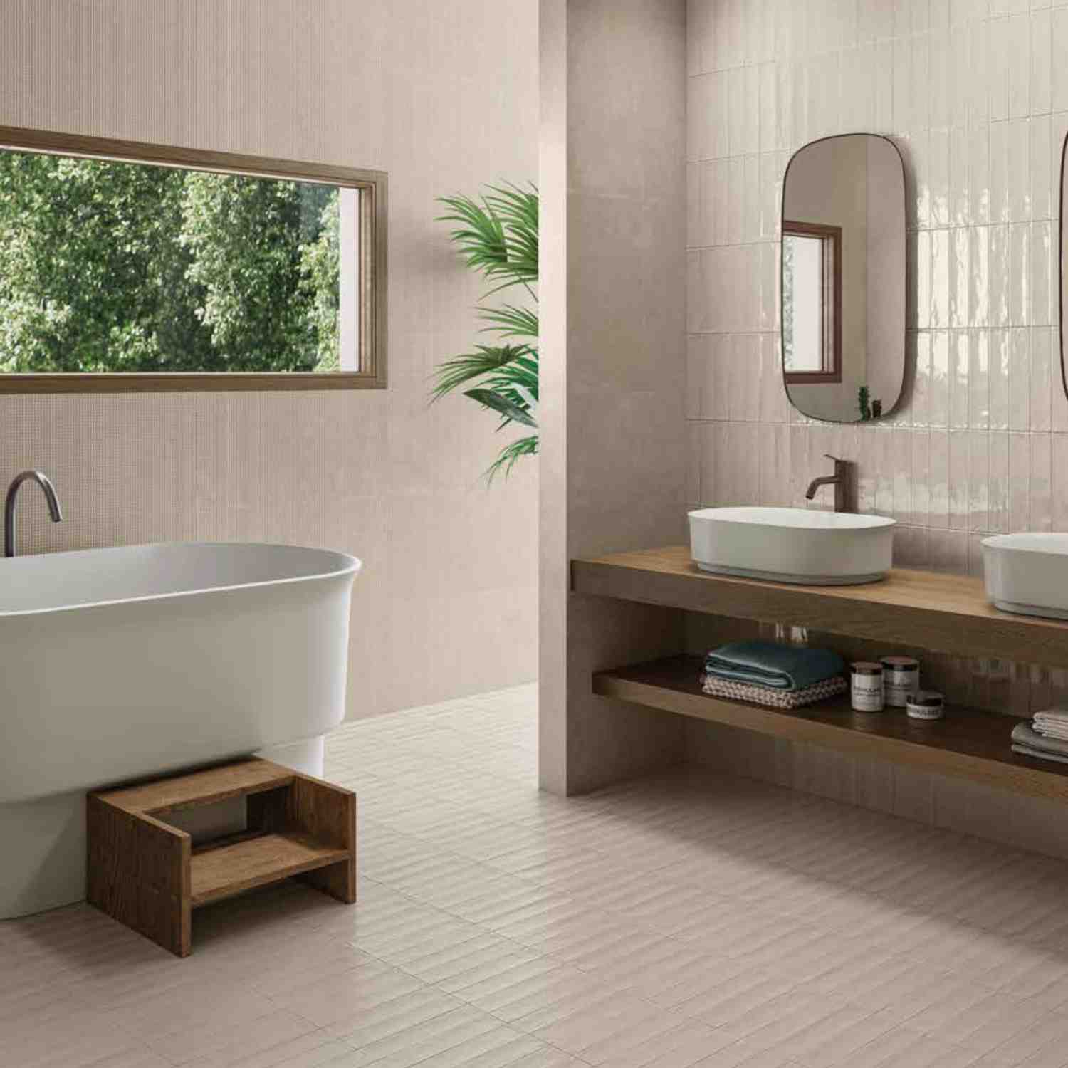 Ergon Total Brick ceramic tiles in cream beige on walls and floor of a spacious bathroom with freestanding white bathtub, vessel sink on wooden vanity, and natural light