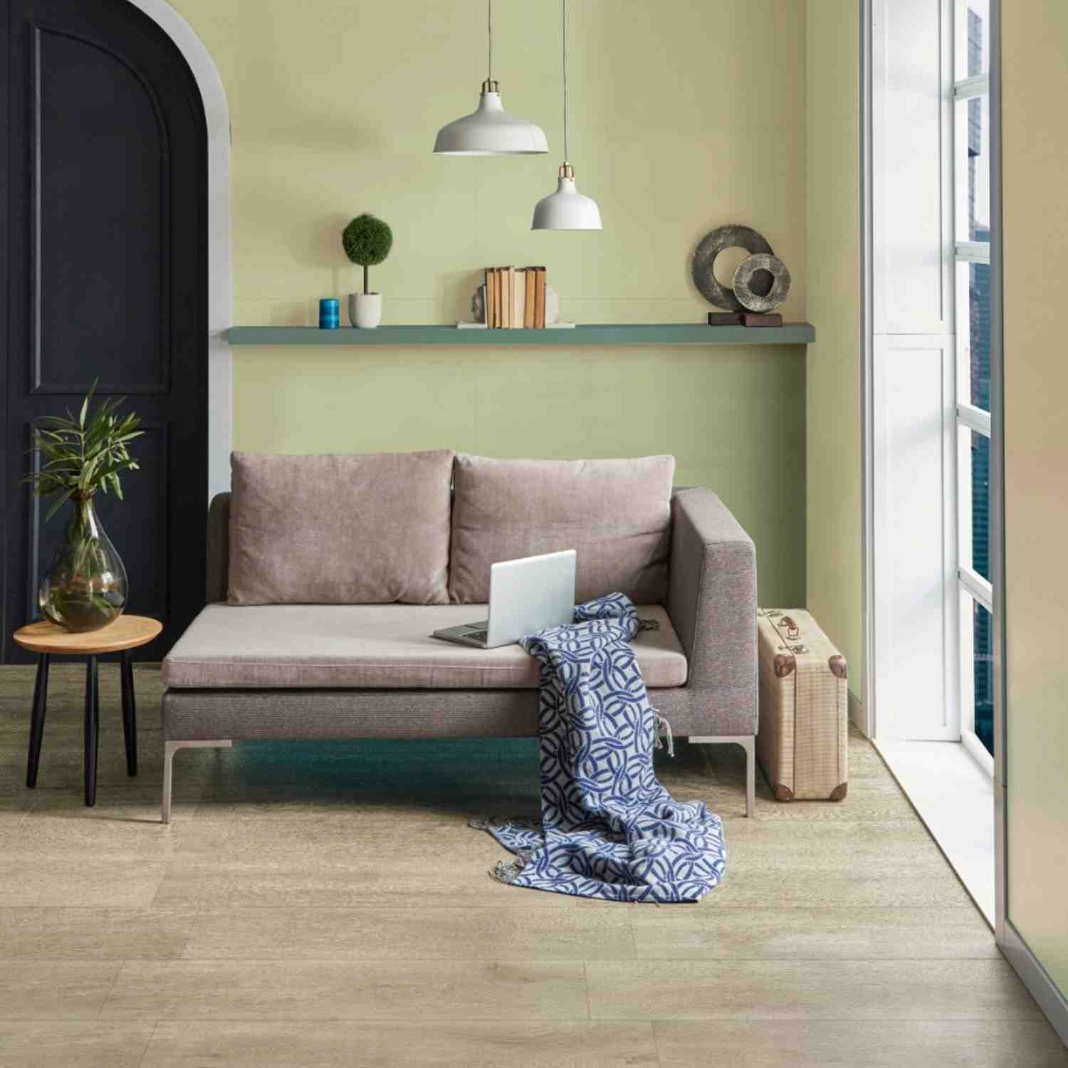 Florina Urban Cement porcelain floor tiles in a cozy living room with grey sofa, teal accent wall with arch doorway, pendant lights, and patterned throw blanket