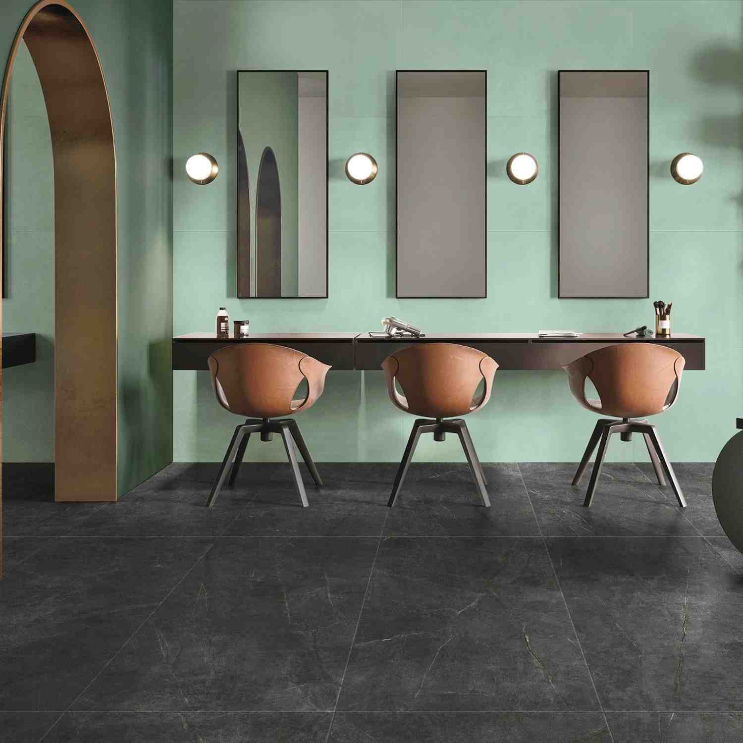 Florina Urban Cement porcelain floor tiles in dark charcoal in a stylish commercial space with mint green walls, copper chairs, wall mirrors, and globe lights