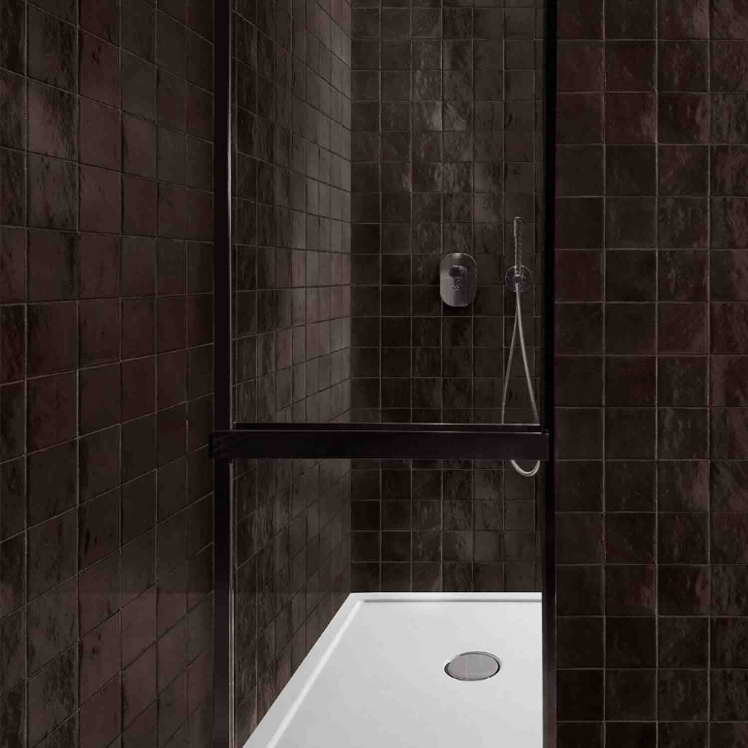 Marazzi Zellige glossy ceramic wall tiles in dark charcoal brown in shower enclosure with chrome fixtures, recessed shelf niche, and white shower base